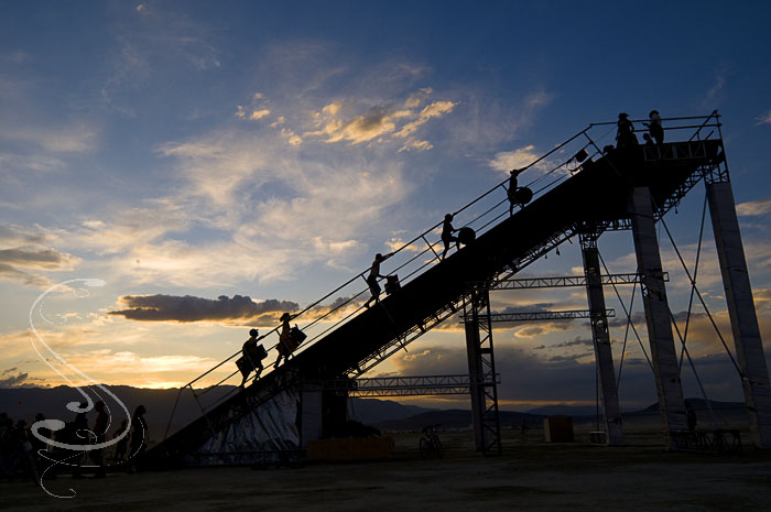 The Wedge, an installation by Jon Morris, was one of my favorite art installations out on the playa. I am always partial to things I can play on, and this giant slide was no exceptions. After a few test slides, I figured a way to ride it standing up all the way down on two pieces of cardboard, like skiing. Got a few cool stickers for my efforts.