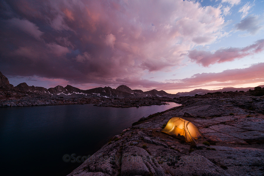 Lakeside camp and stormy sunset over Isoscolese peak, Mt. Winchell, Thunderbolt Peak, and North Palisade peak from a lake in the Dusy Basin in the High Sierra mountain range in California.