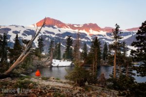 woman sips coffe at sunrise at high alpine lake