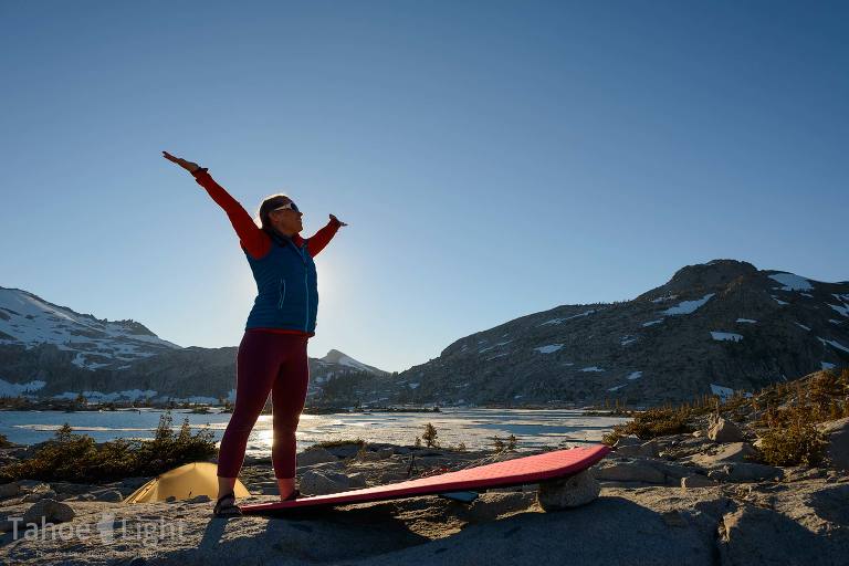 woman does yoga by mountain lake