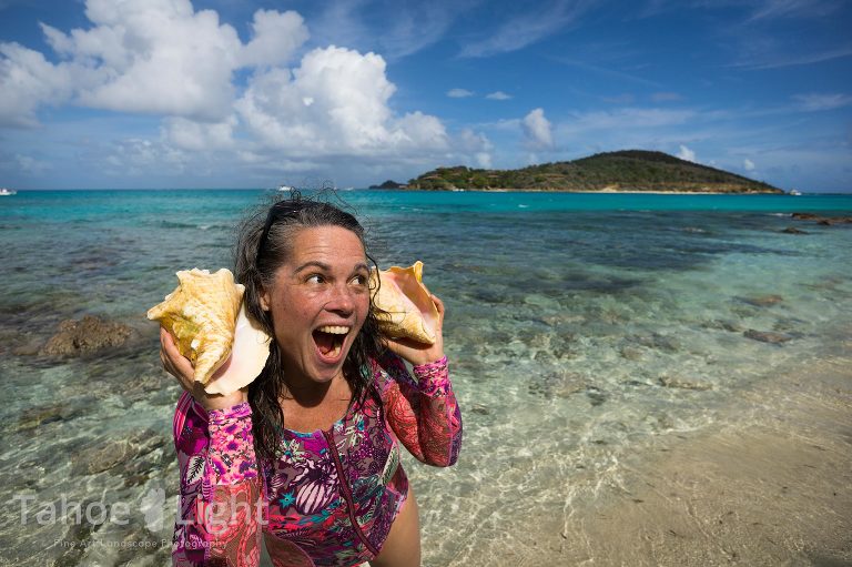 woman with conch shells up to her ears on tropical island