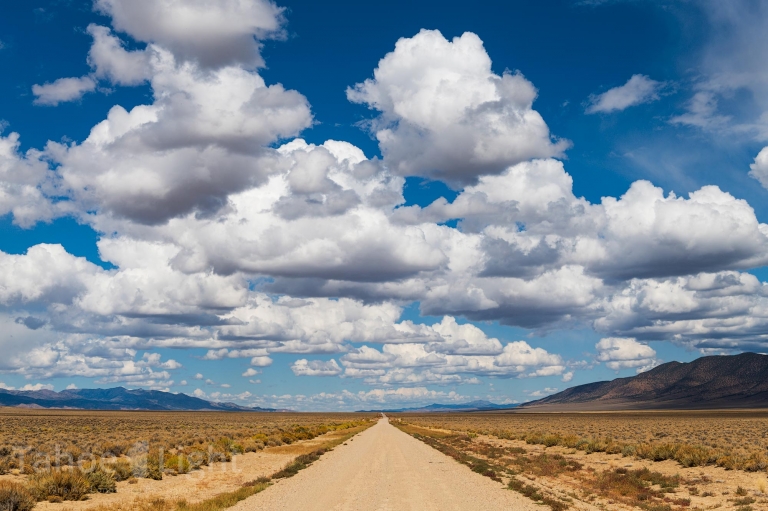 photograph of clouds over lonely straight road